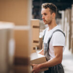 Pracownik/pracownica produkcji young man working warehouse with boxes 1