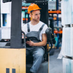 Operator/ka wózka widłowego young man working warehouse with boxes 2